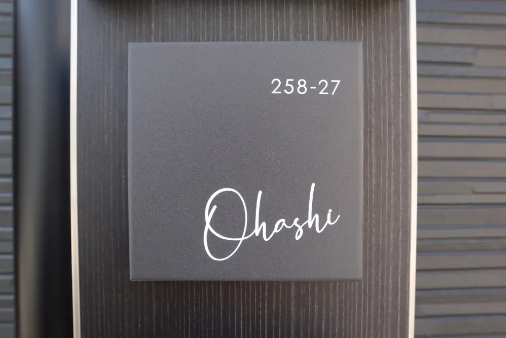 ソフトブラックのタイル表札に白の塗料で書かれたOhashiの文字