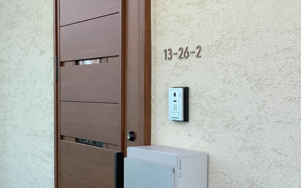 玄関ドア横に取り付けられたゴールドカラーのおしゃれな数字のステンレス切り文字オーダー表札施工事例