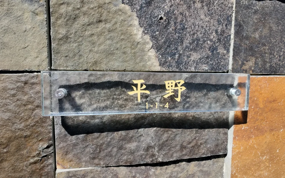 クリアなきらめきの高透過ガラスにゴールドの文字が彫刻されたおしゃれなオーダー表札の施工事例