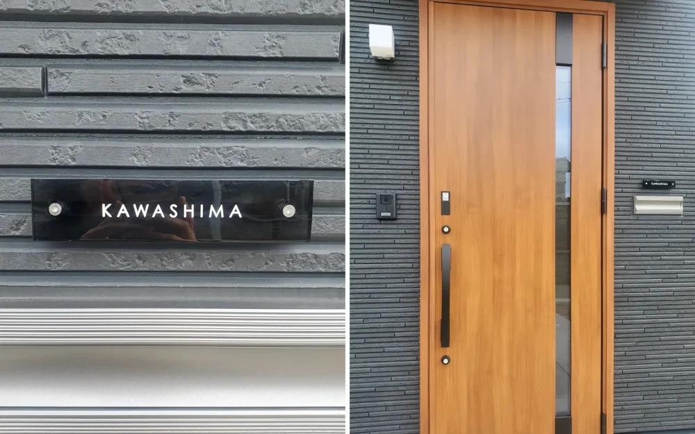 ブラック系の壁にグレーのガラス表札を付けている家。