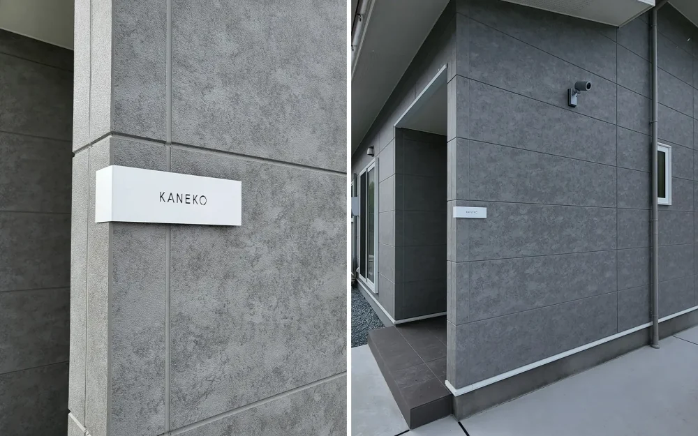 グレーの壁に白のステンレス表札を付けている家。