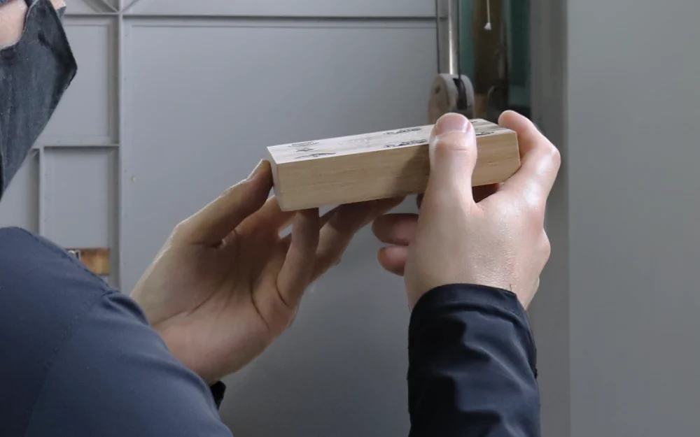 木製の表札を手にちり検品する職人