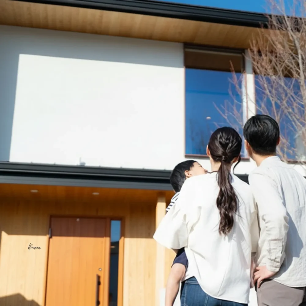 表札を取付けた新築のわが家を眺める家族